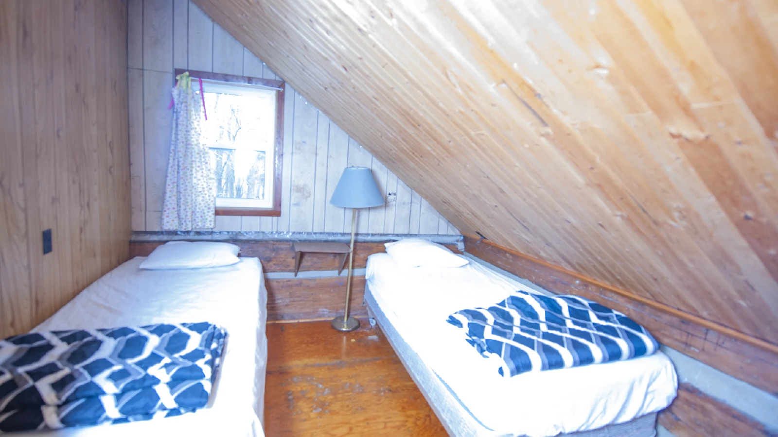 Pigeon Lake Resort Cottage Seven.&nbsp; Upstairs bedroom with two single beds and sloped wooden ceiling in a cottage.